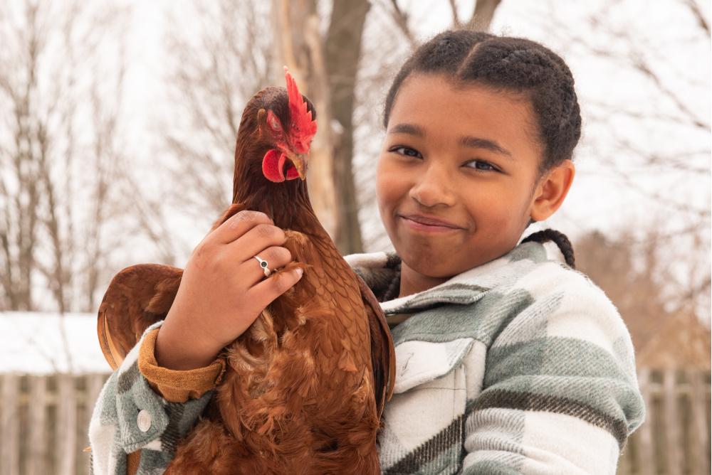 A young girl holding a chicken showing compassion to animals